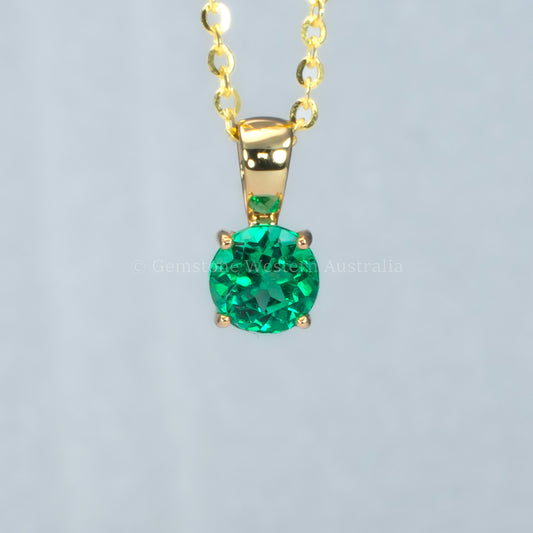 Colombian emerald gold pendant in gray background
