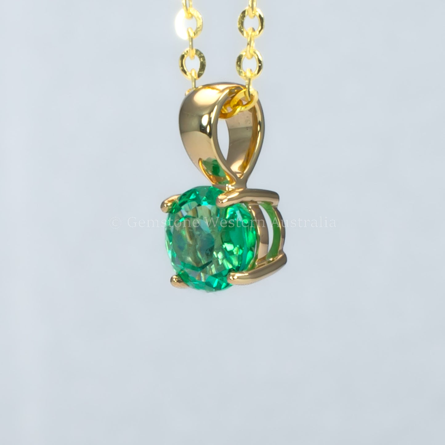 side view of Colombian emerald gold pendant in gray background