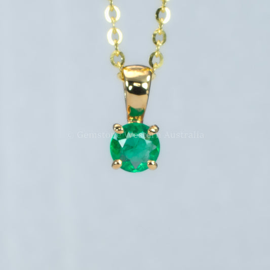 petite emerald pendant in gold in gray background 