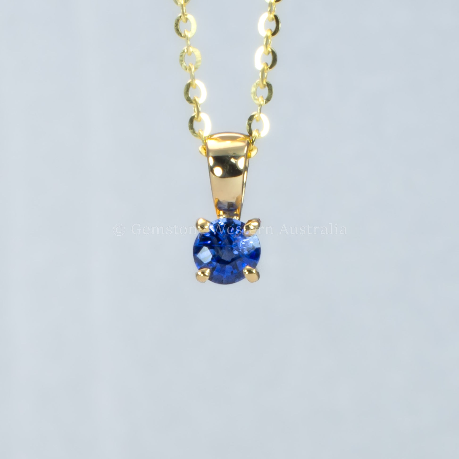 yellow gold royal blue sapphire pendant in gray background