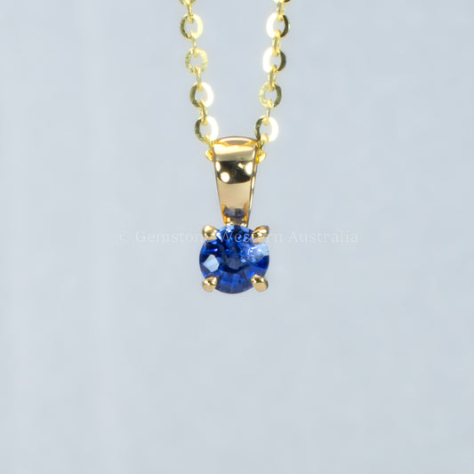 yellow gold royal blue sapphire pendant in gray background