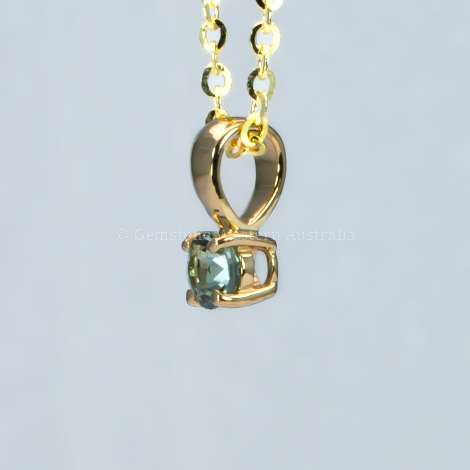 side view of yellow gold alexandrite pendant in gray background