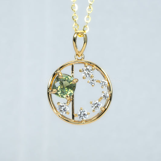 Open circle gold pendant with alexandrite gemstone and small diamonds on a light gray background
