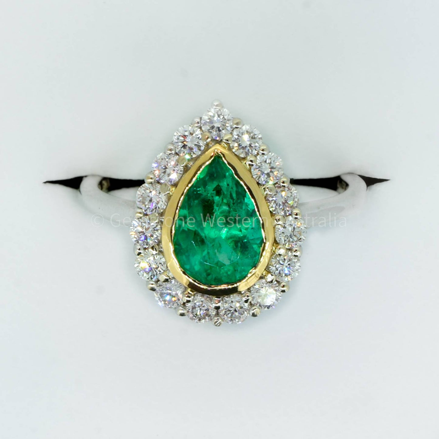 Bezel Set Emerald in a Diamond Halo Ring in 18K Gold