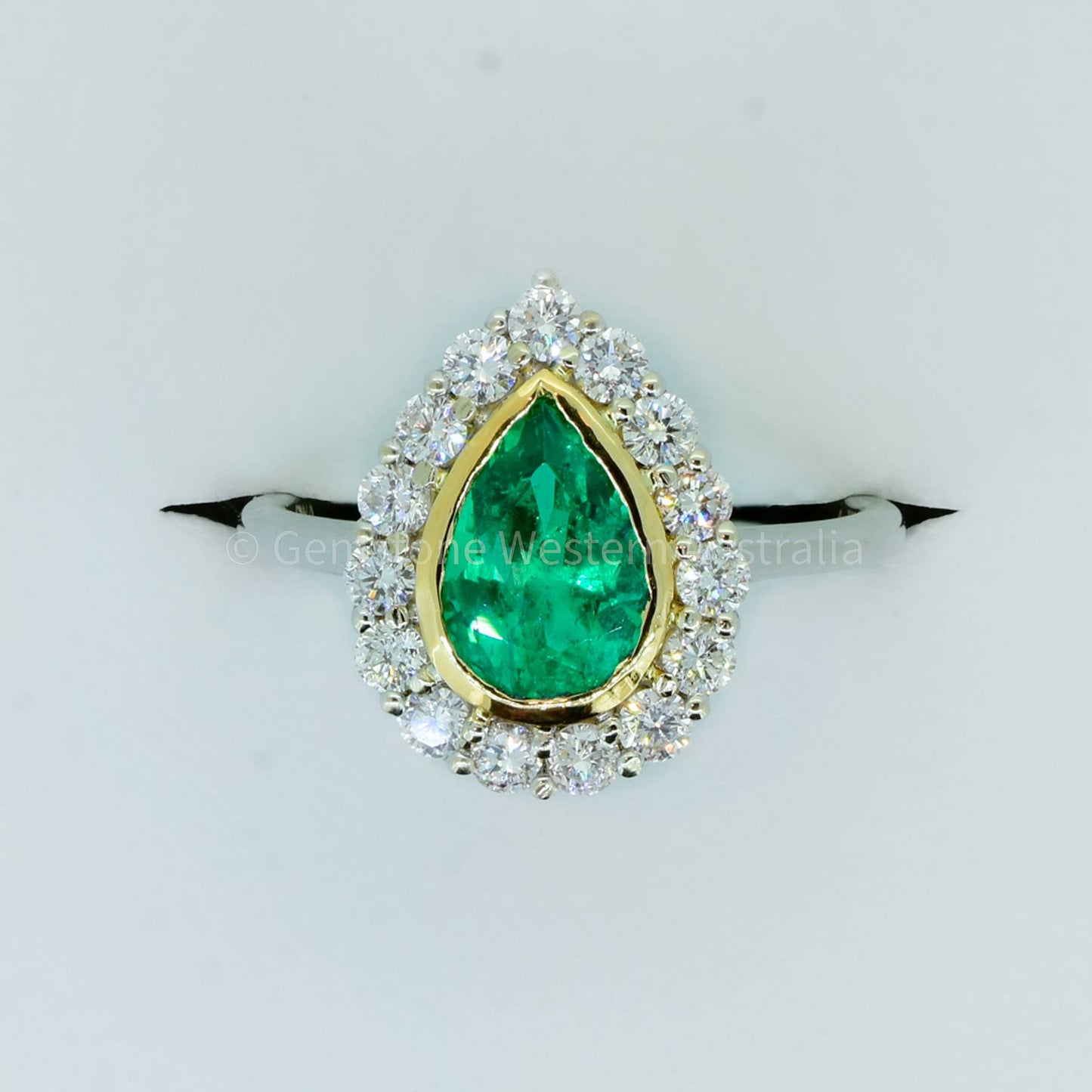 Bezel Set Emerald in a Diamond Halo Ring in 18K Gold