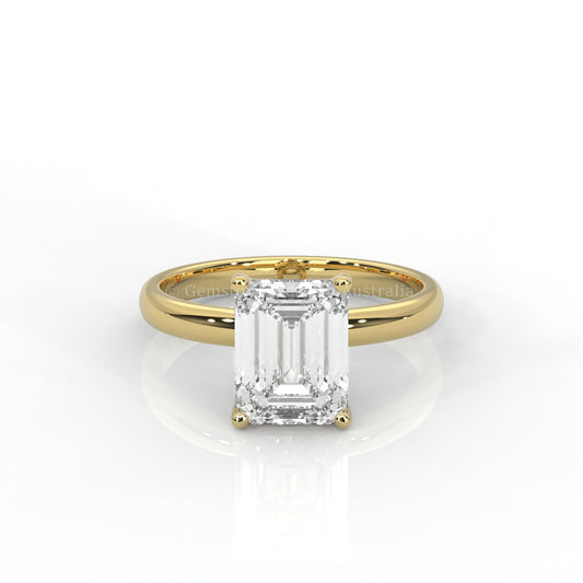 yellow gold solitaire ring with emerald-cut diamond in a white background
