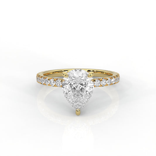 Yellow gold ring with a pear-cut diamond and smaller diamonds on the band against a white background
