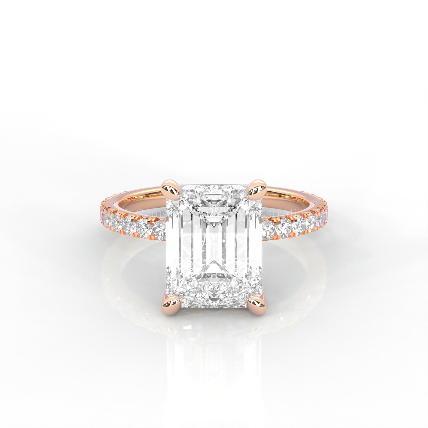 Rose gold ring with an emerald-cut diamond and smaller diamonds on the band against a white background