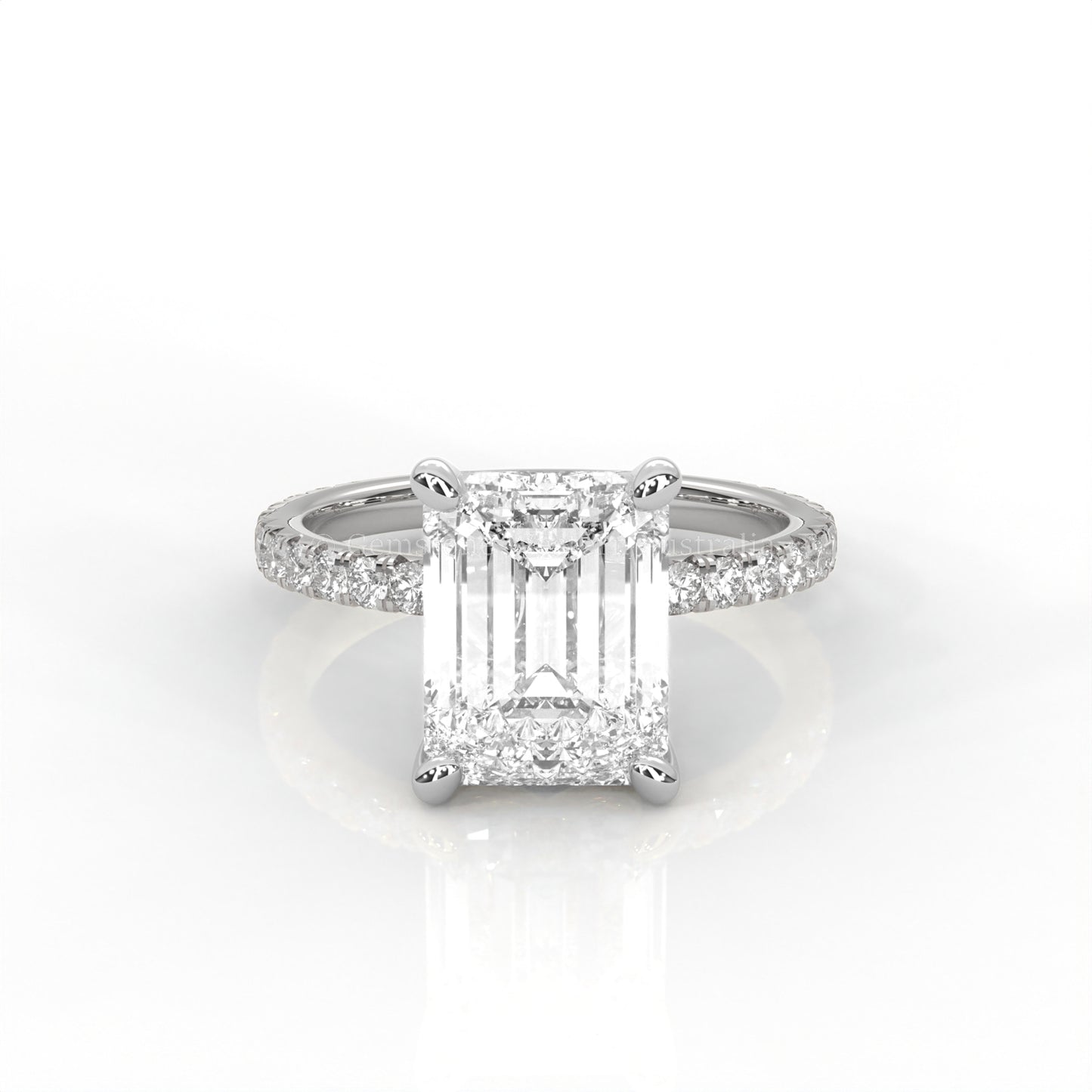 White gold ring with an emerald-cut diamond and smaller diamonds on the band against a white background