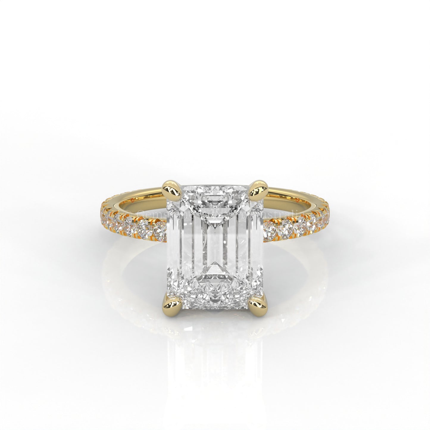 Yellow gold ring with an emerald-cut diamond and smaller diamonds on the band against a white background