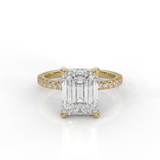 Yellow gold ring with an emerald-cut diamond and smaller diamonds on the band against a white background