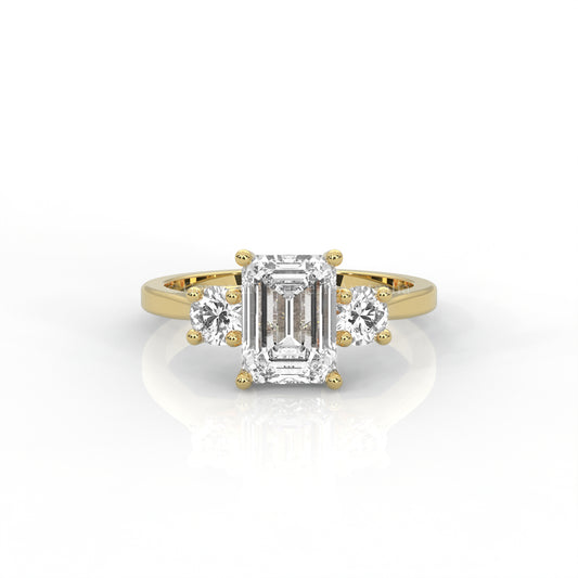 yellow gold three stone ring with round side diamonds and emerald-cut centre stone on white background