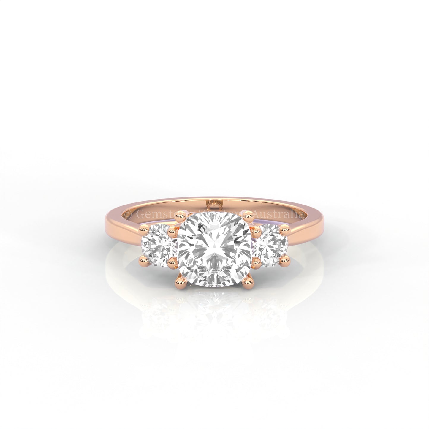 Rose gold three stone ring with round side diamonds and cushion centre stone on white background