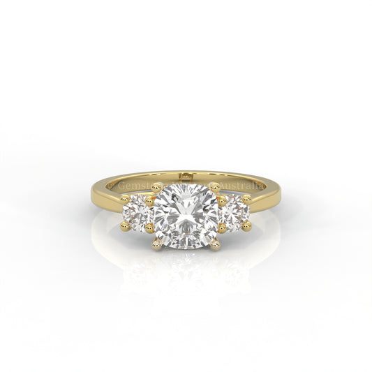 yellow gold three stone ring with round side diamonds and cushion centre stone on white background