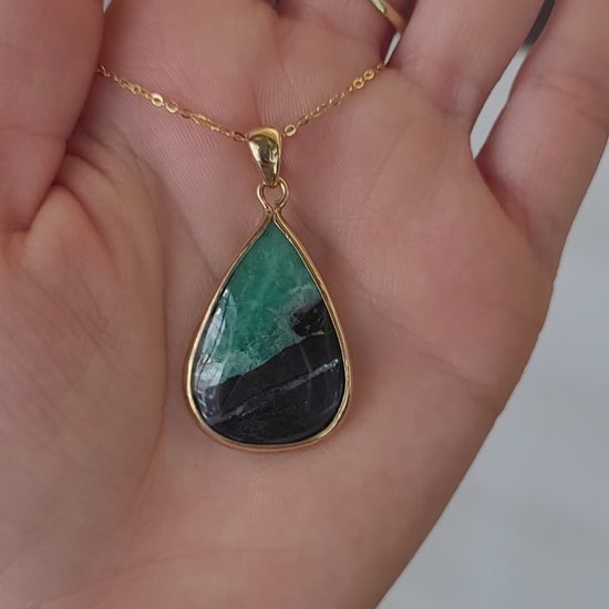 video of emerald in matrix gold pendant on light gray background