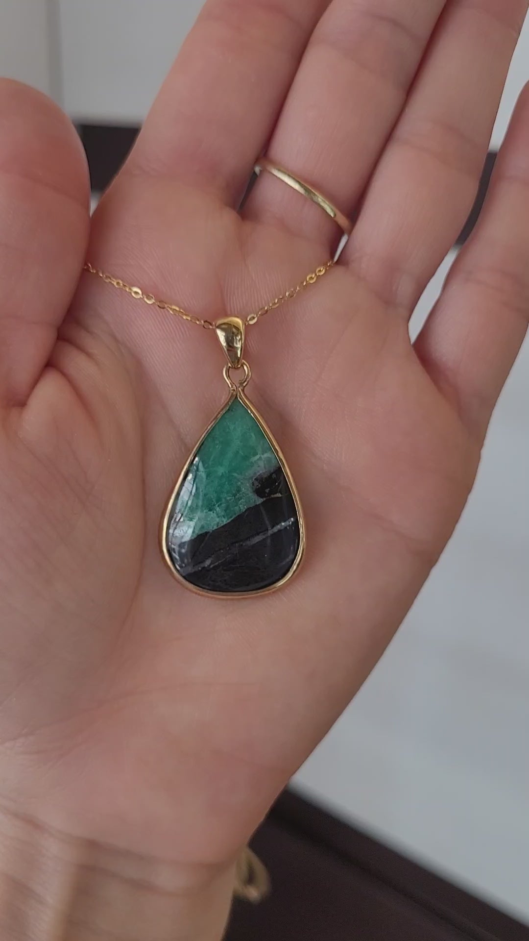 video of emerald in matrix gold pendant on light gray background