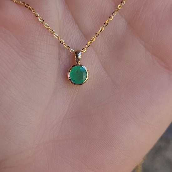 video of Round Colombian Emerald Bezel Set Pendant in 18K Yellow Gold – 0.62ct held on hand