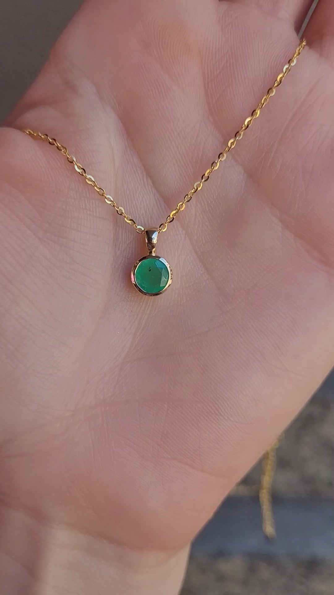 video of Round Colombian Emerald Bezel Set Pendant in 18K Yellow Gold – 0.62ct held on hand