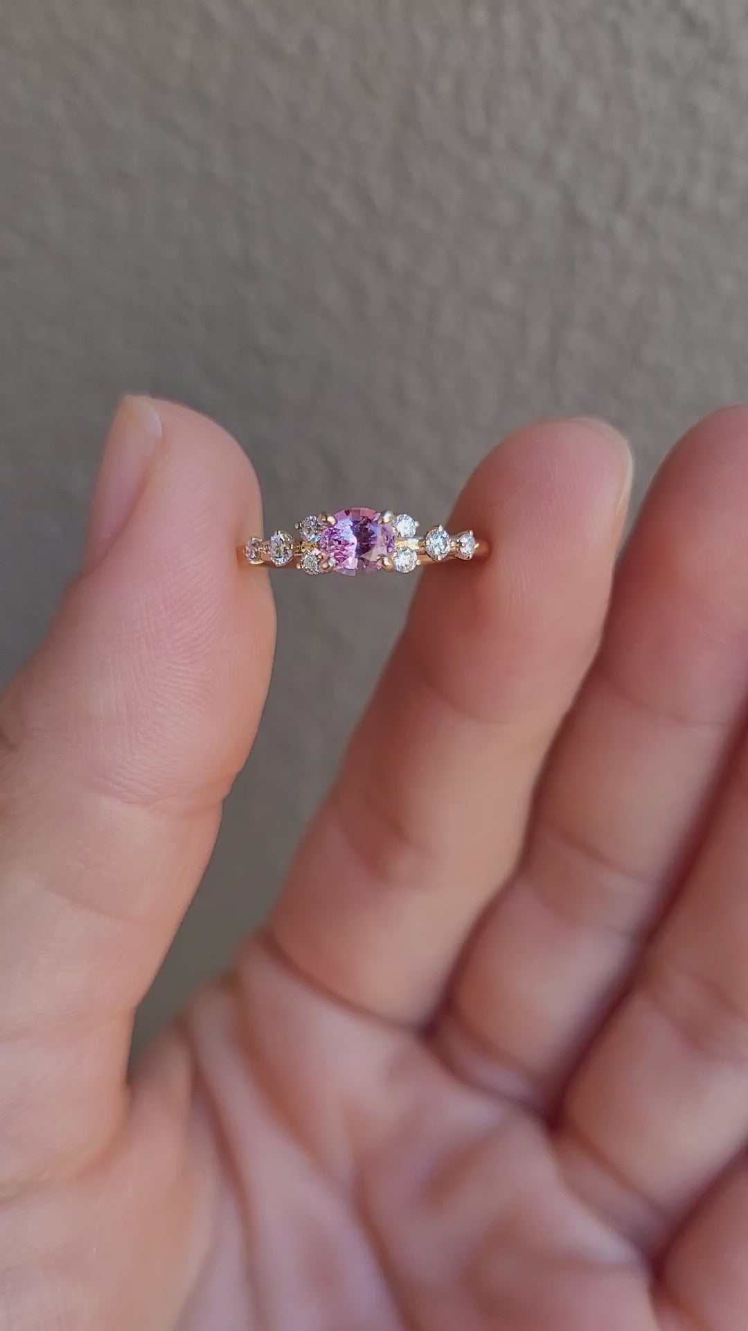 video of Gold ring with natural pink sapphire and diamonds on a gray background