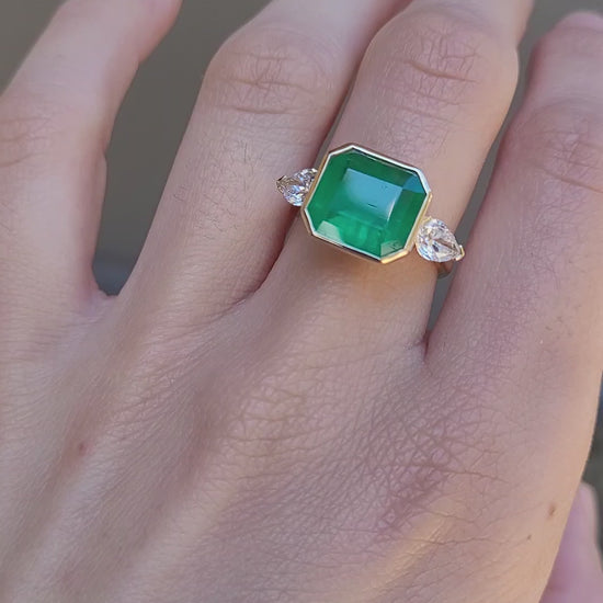 video of hand wearing a Colombian Emerald and Diamond Ring in 18K Yellow Gold – East West Emerald Cut in neutral background 