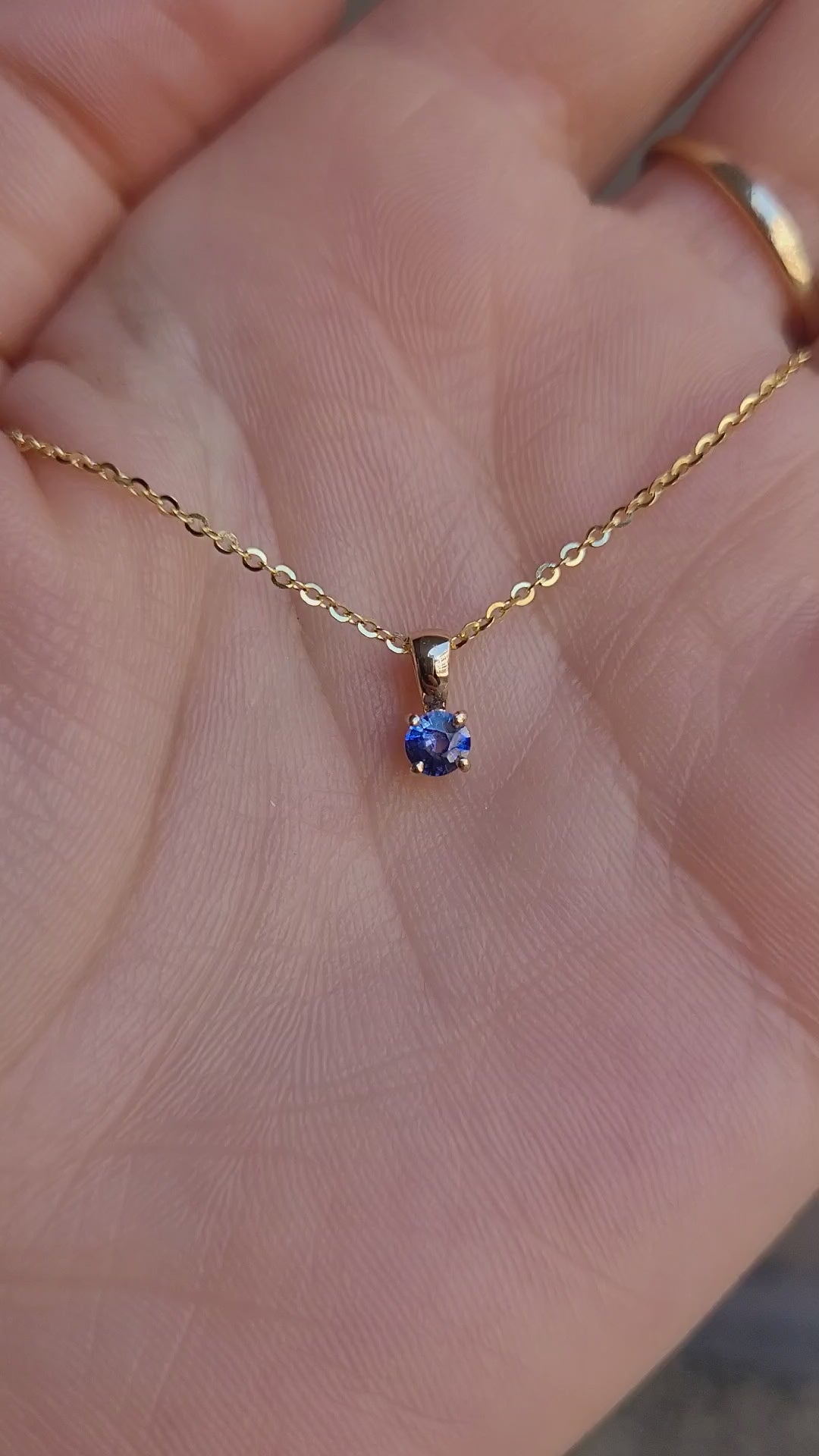 video of yellow gold royal blue sapphire pendant in gray background