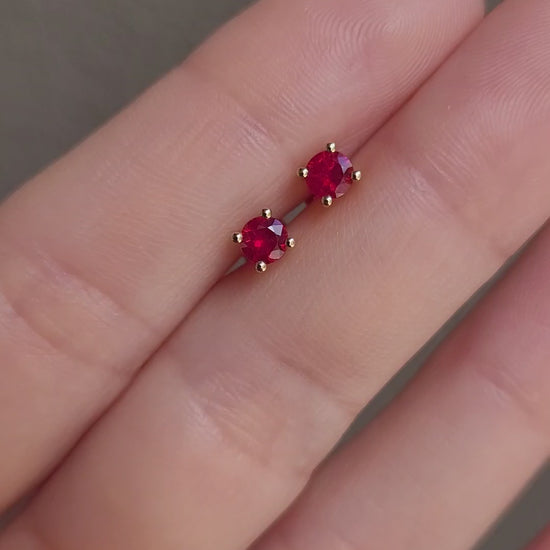video of Natural Ruby Stud Earrings in 18K Yellow Gold held between fingers in neutral background