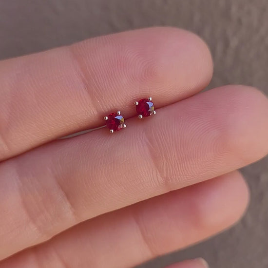 video of ruby earrings in platinum held between fingers against a neutral background