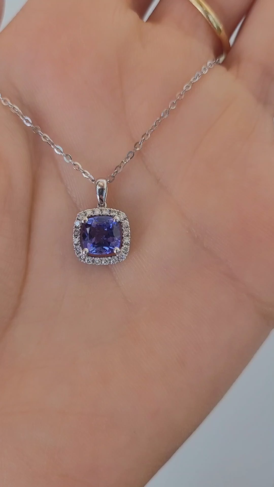 video on hand of Natural tanzanite diamond pendant in white gold in gray background