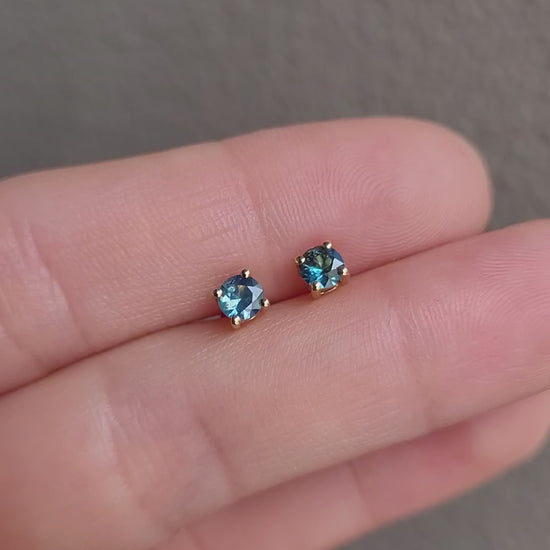 video of Australian teal blue sapphire gold stud earrings in gray background