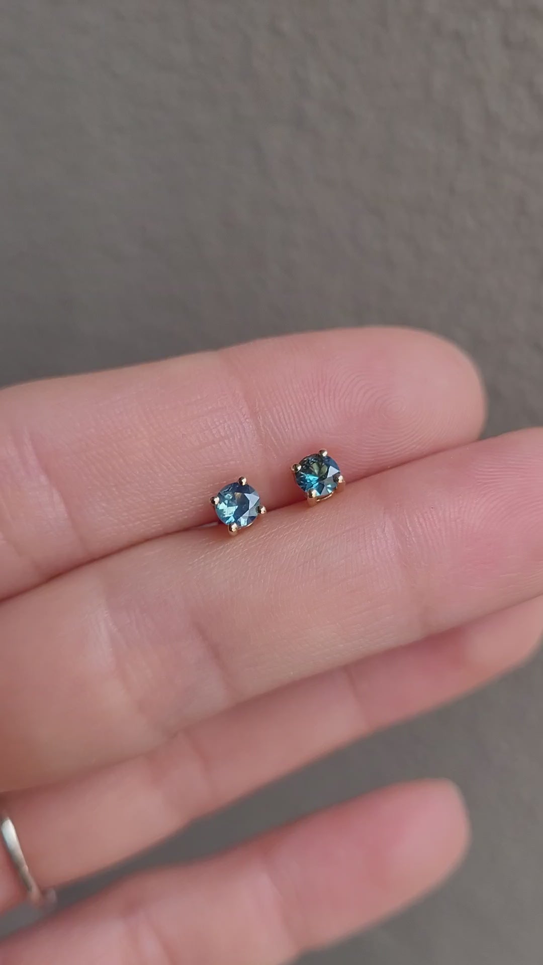 video of Australian teal blue sapphire gold stud earrings in gray background