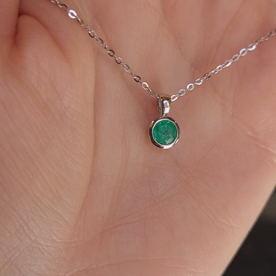 video of Platinum necklace with an emerald pendant held on hand
