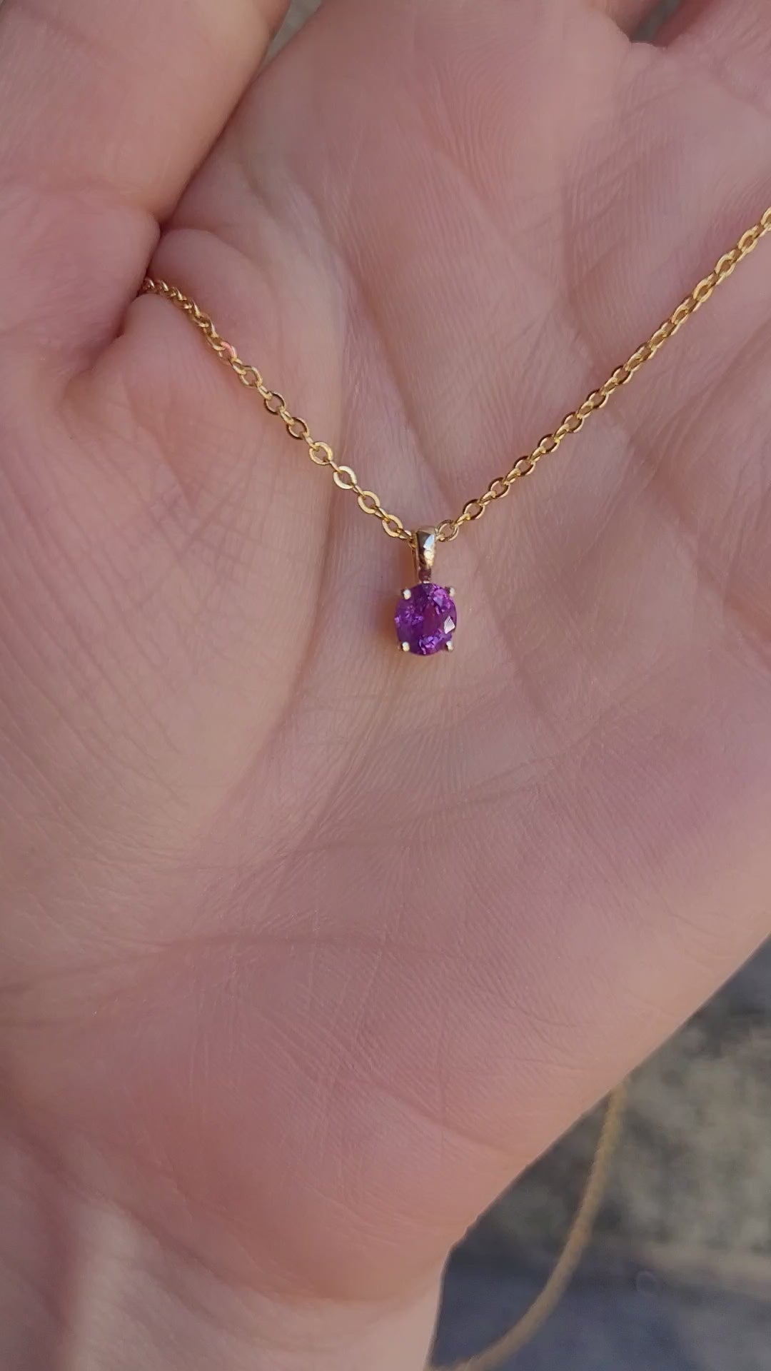video of a Natural Unheated Pink Sapphire Pendant in 18K Yellow Gold held in a hand