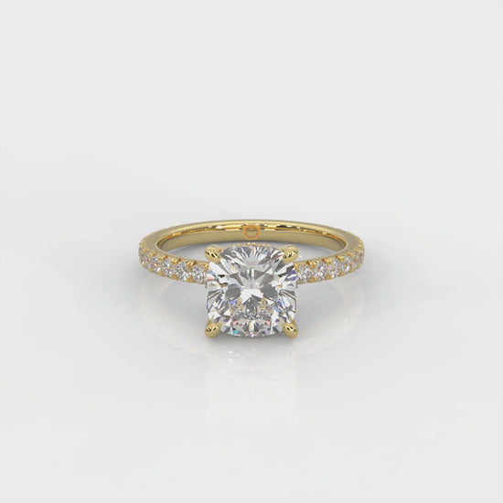 video of yellow gold ring with a cushion cut diamond and smaller diamonds on the band against a white background