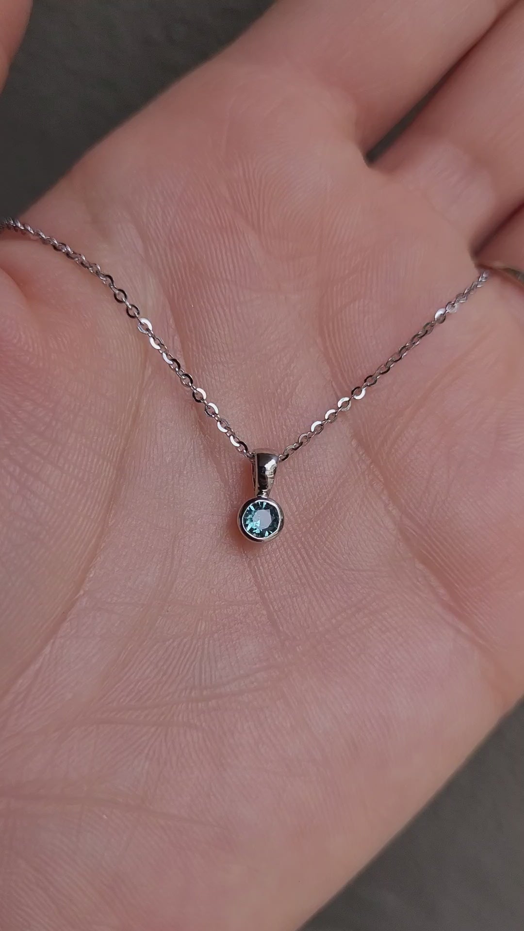 video of Australian teal sapphire platinum pendant in gray background