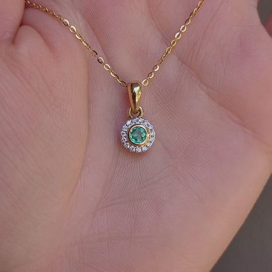 video of Natural Colombian Emerald and Diamond Halo pendant on a hand