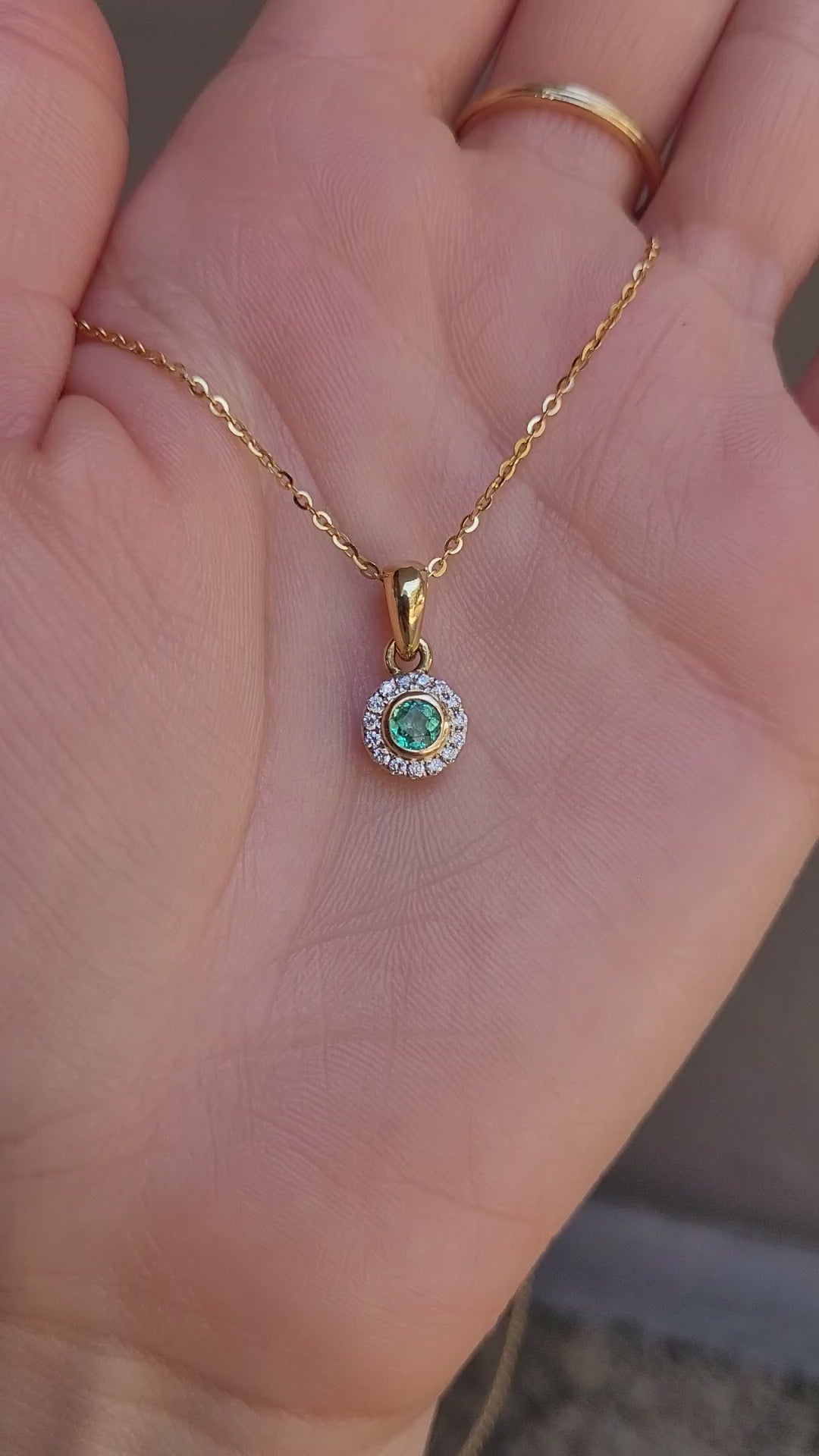 video of Natural Colombian Emerald and Diamond Halo pendant on a hand
