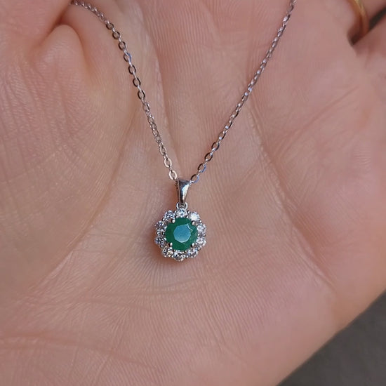 video on hand of Colombian emerald pendant on grey background 