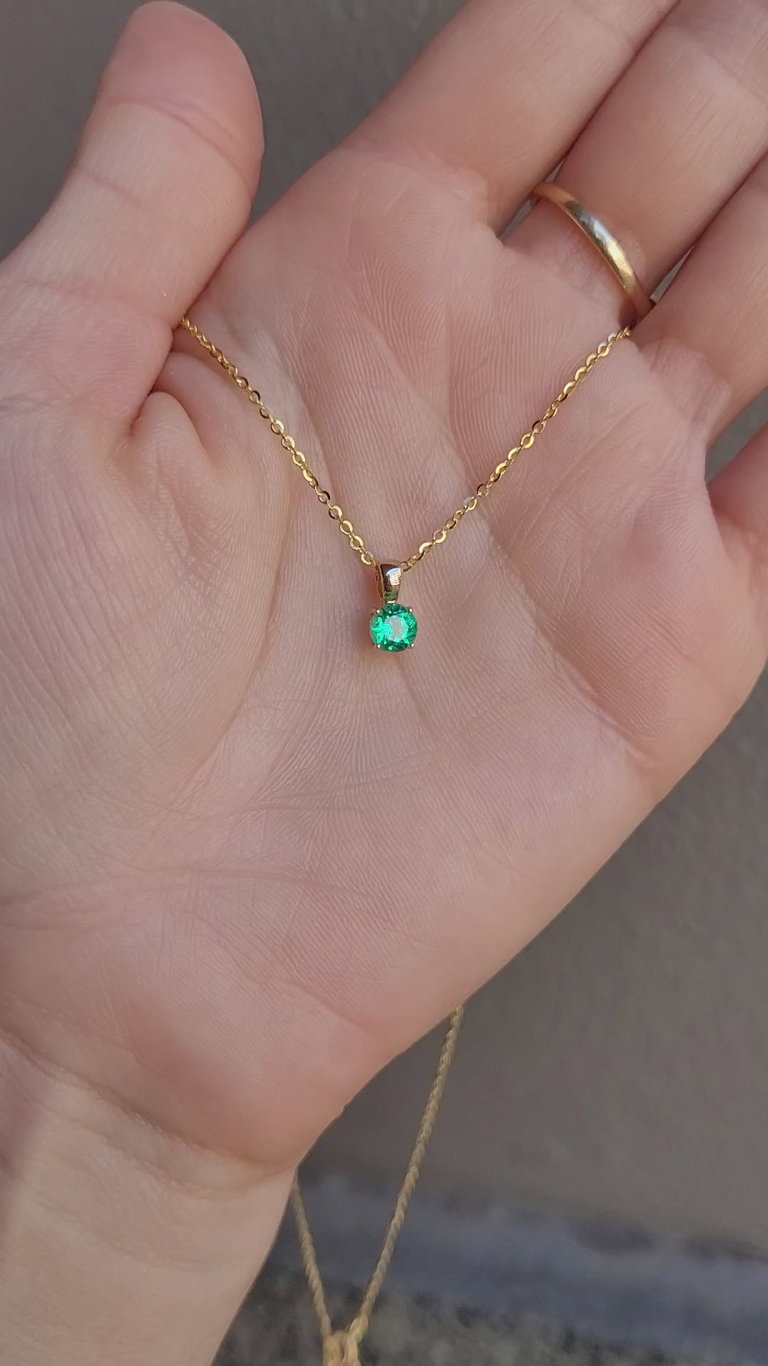 video of Colombian emerald gold pendant in gray background