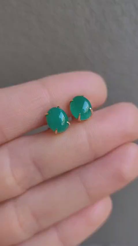 video of Cabochon emerald earrings held between fingers against a neutral background