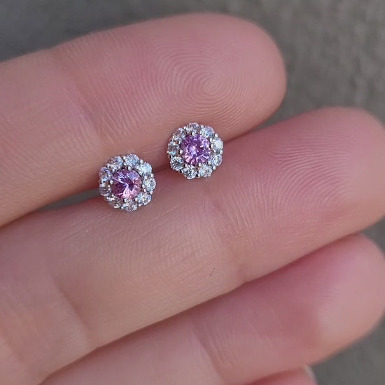 video of a pair of pink sapphire earrings held between fingers against a neutral background
