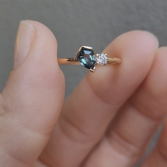 video of Teal Sapphire and Diamond Toi et Moi Ring in 18K Yellow Gold held between fingers in neutral background 