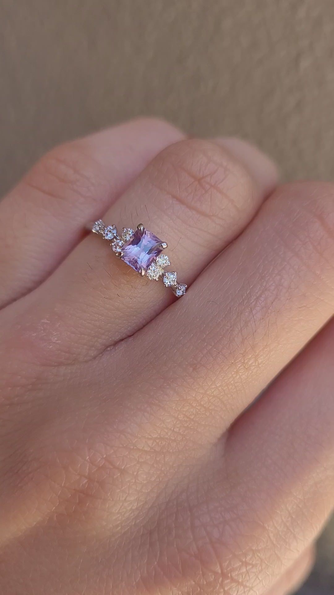 video on hand of Platinum pink sapphire ring with natural diamonds in gray background