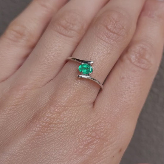 video on hand of white gold ring with natural Colombian emerald in light gray background