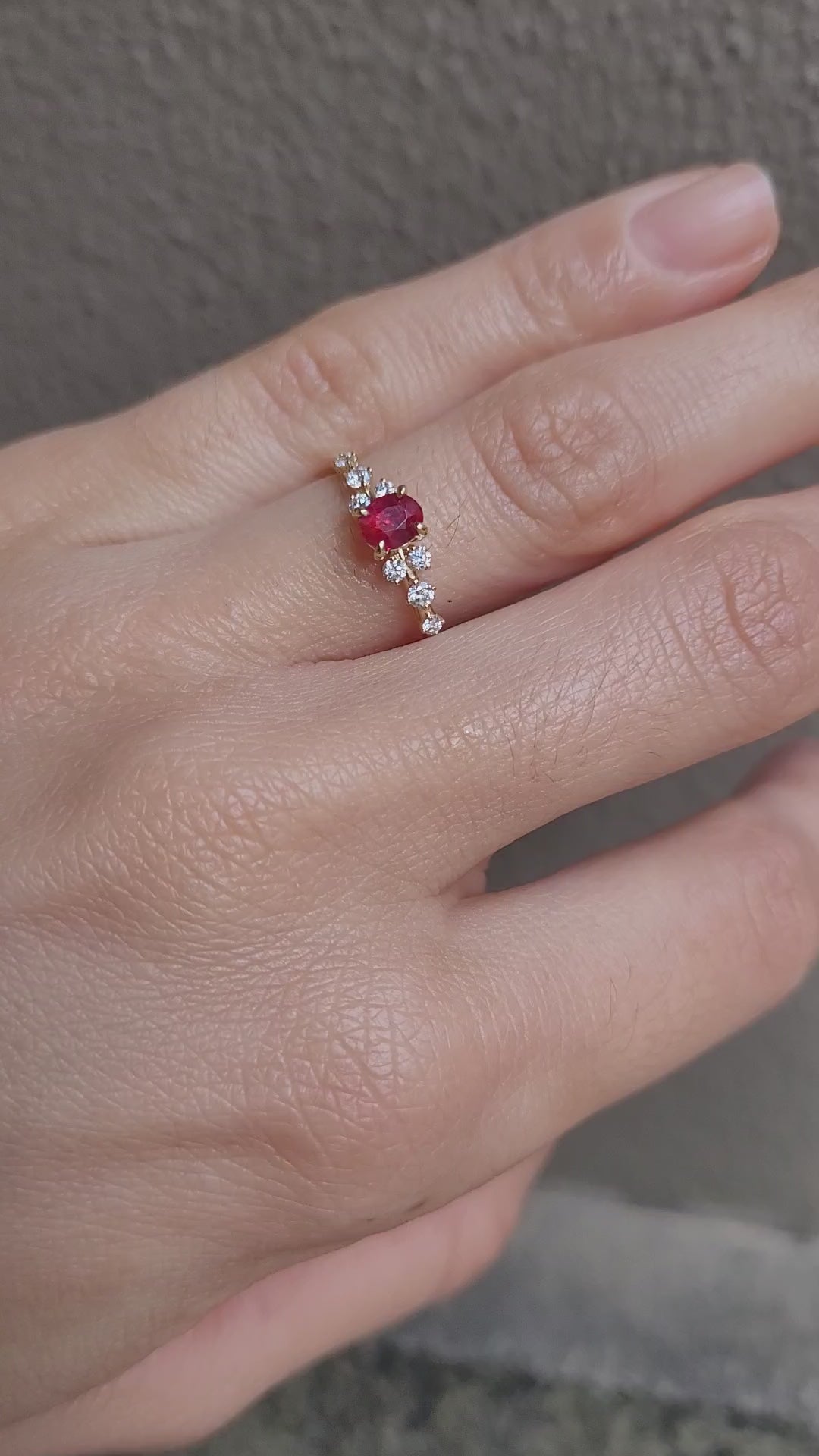 video of hand wearing ruby and diamonds gold ring in yellow gold in neutral background