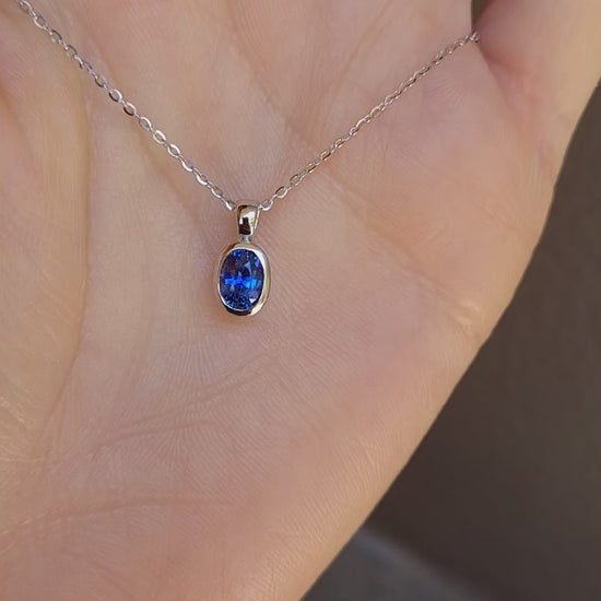 video of platinum pendant with blue sapphire held on hand