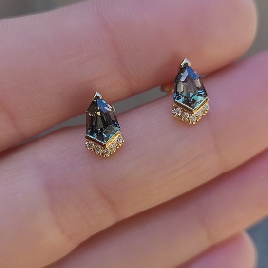 video of Shield Cut Teal Sapphire Diamond Stud Earrings in 18K Yellow Gold held in between fingers