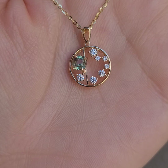 video of open circle gold pendant with alexandrite gemstone and small diamonds on a hand