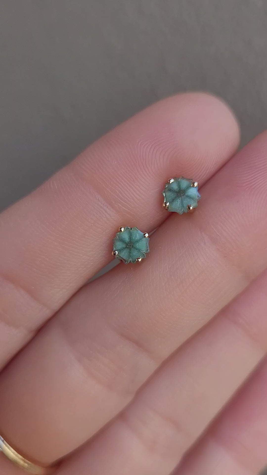 video of pair of natural emerald stud earrings set in  18K yellow gold