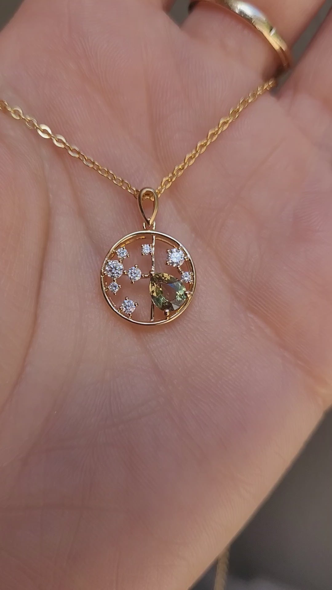 video of hand holding a Natural Alexandrite and Diamond Pendant in 18K Yellow Gold – 0.63ct Pear Cut in neutral background