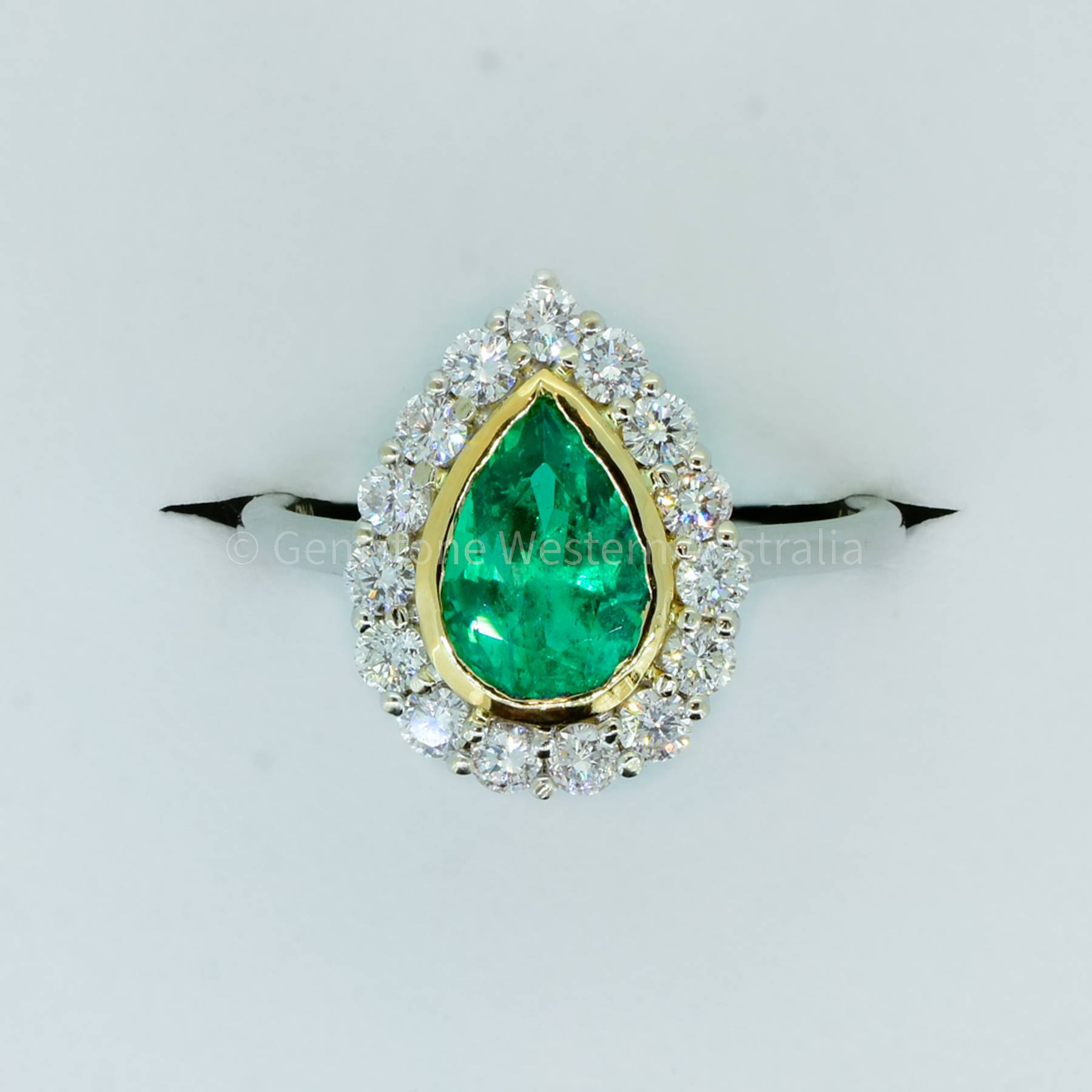 Bezel Set Emerald in a Diamond Halo Ring in 18K Gold